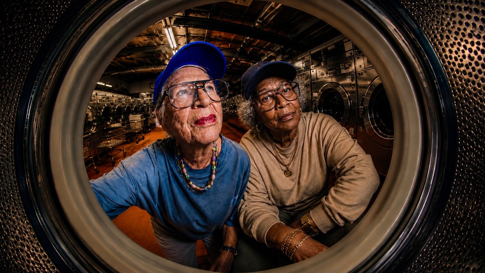 The Laundry Ladies looking through a dryer door in a laundromat